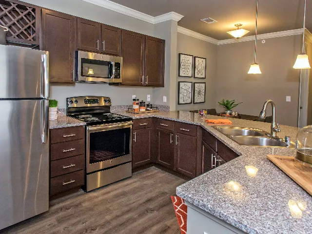 Corner kitchen with stainless steel appliances and stone counters.