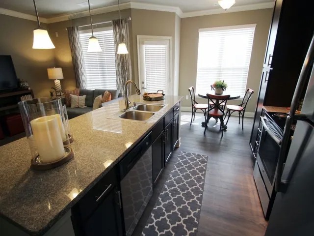 View of kitchen with stone counters, looking through to the dining area.