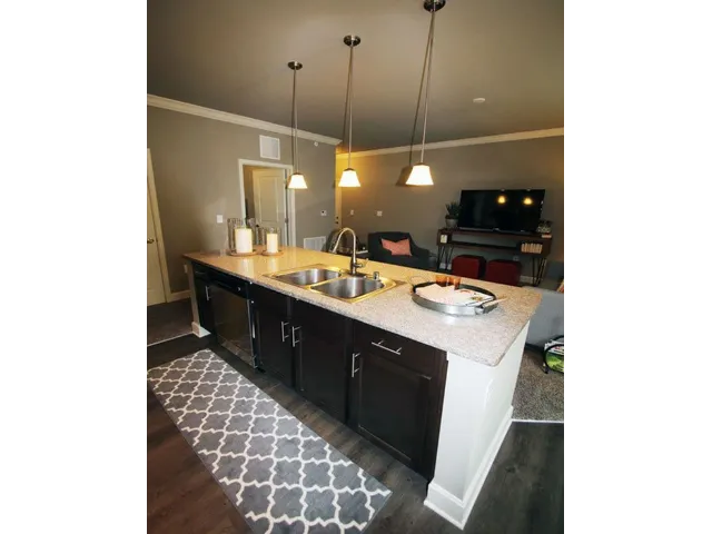 View from kitchen overlooking stone counters and a breakfast bar, into the living room.