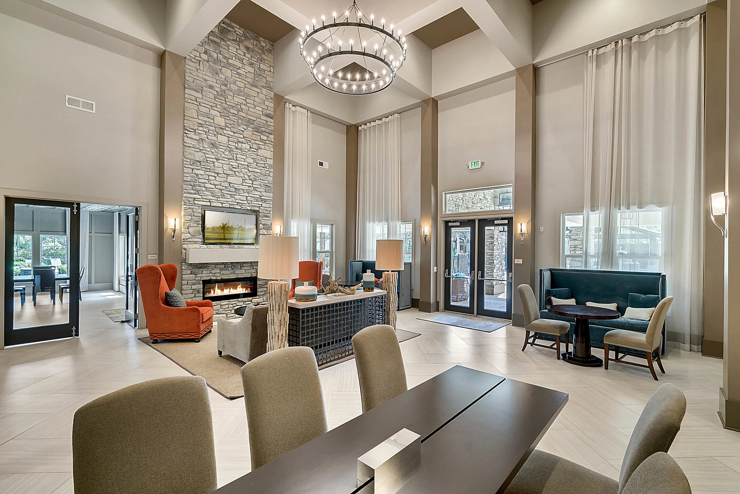 Luxurious living room with high ceilings, stone fireplace, and elegant chandelier, offering a warm and inviting ambiance.