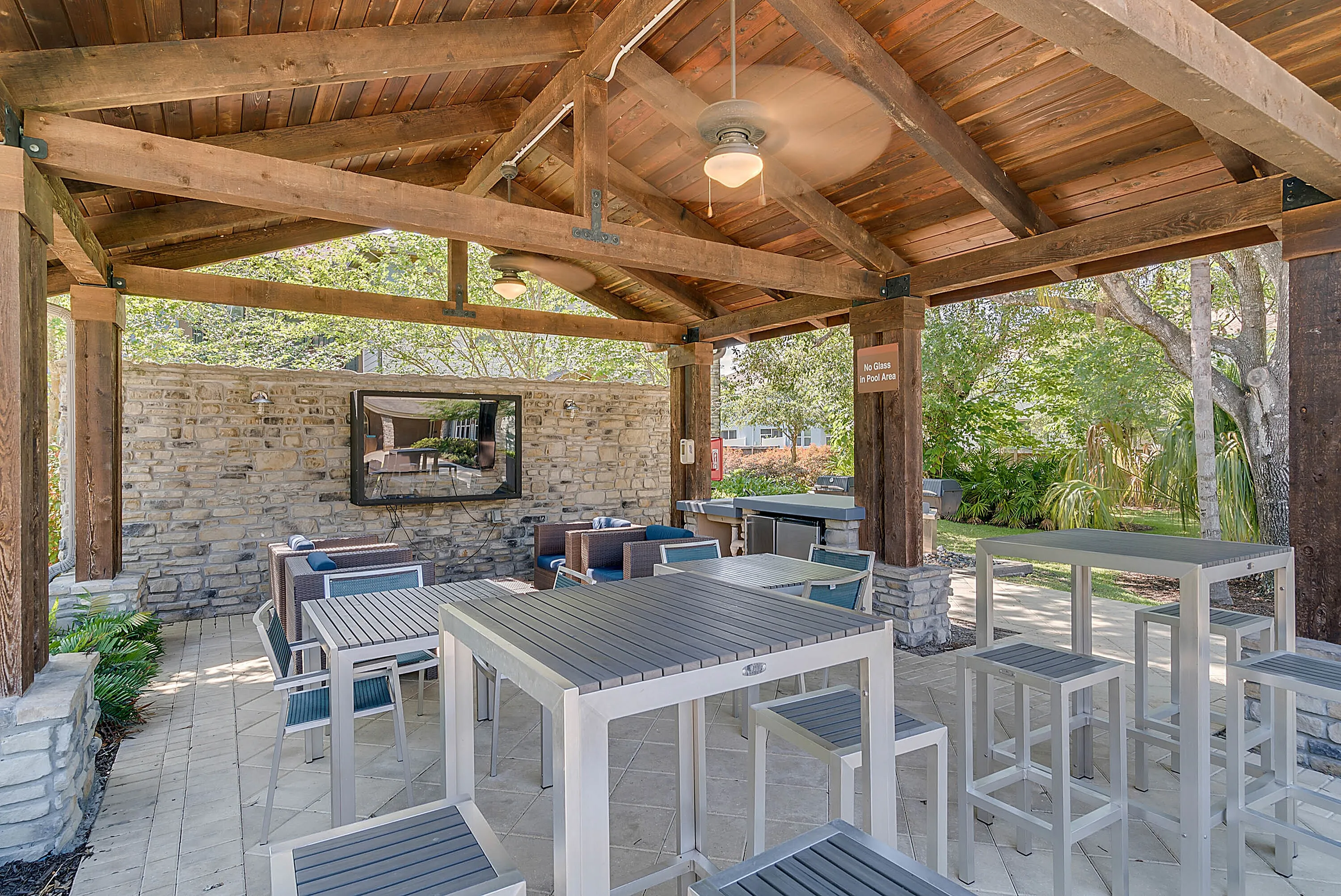 Charming outdoor patio with rustic wooden beams, comfy seating, and vibrant greenery, perfect for relaxation or entertaining.