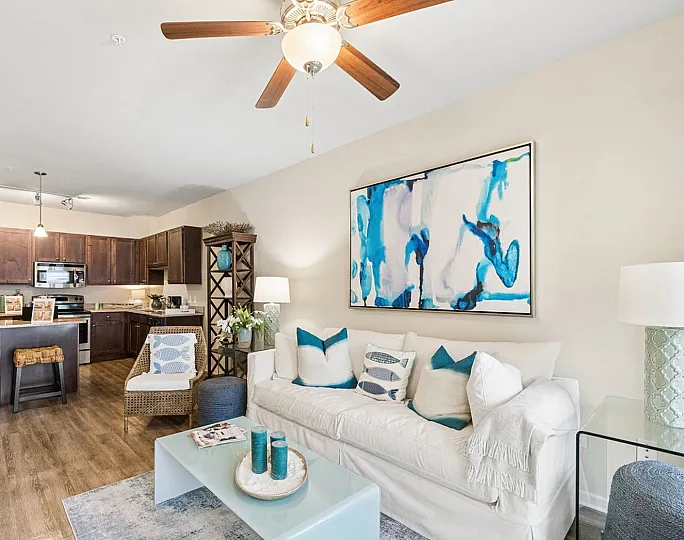 Contemporary open-concept living room with elegant decor, blending seamlessly with a modern kitchen, featuring sleek stainless steel appliances and rich wood cabinetry.