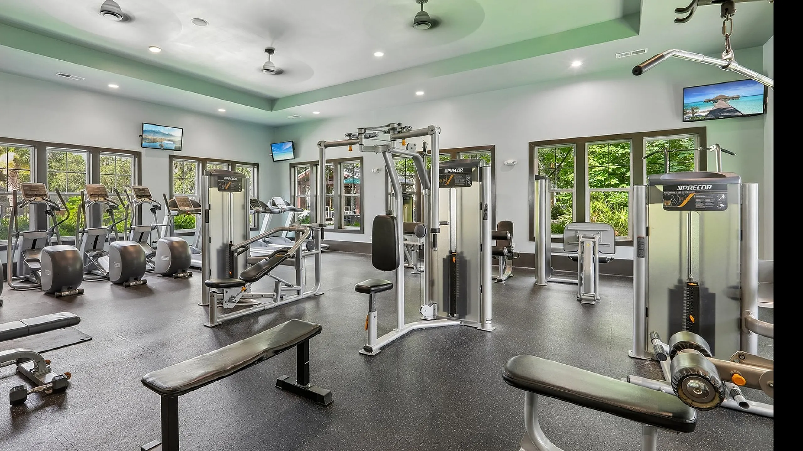 Bright and modern fitness center with state-of-the-art exercise equipment and large windows overlooking lush greenery.