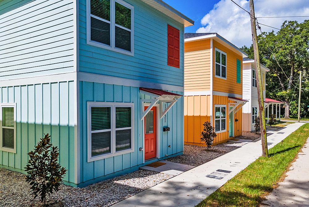 Charming row of colorful townhouses with vibrant facades and modern design, nestled in a serene, lush neighborhood setting.