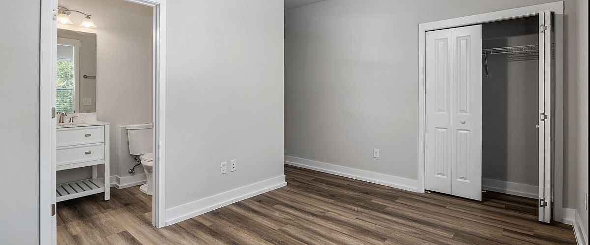 Bright bedroom with modern wood flooring, built-in closet, and attached bathroom with sleek fixtures.