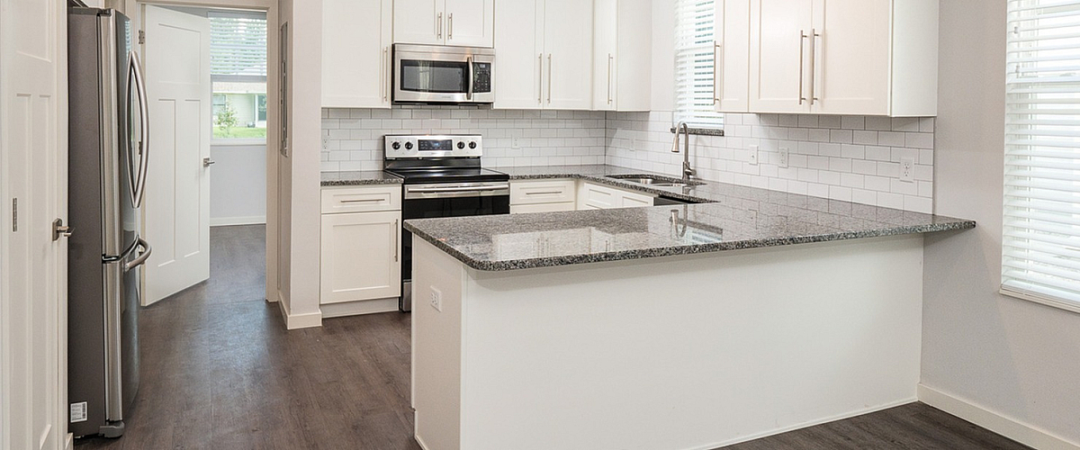 Modern kitchen with sleek white cabinetry, granite countertops, and stainless steel appliances, offering a bright and inviting atmosphere.