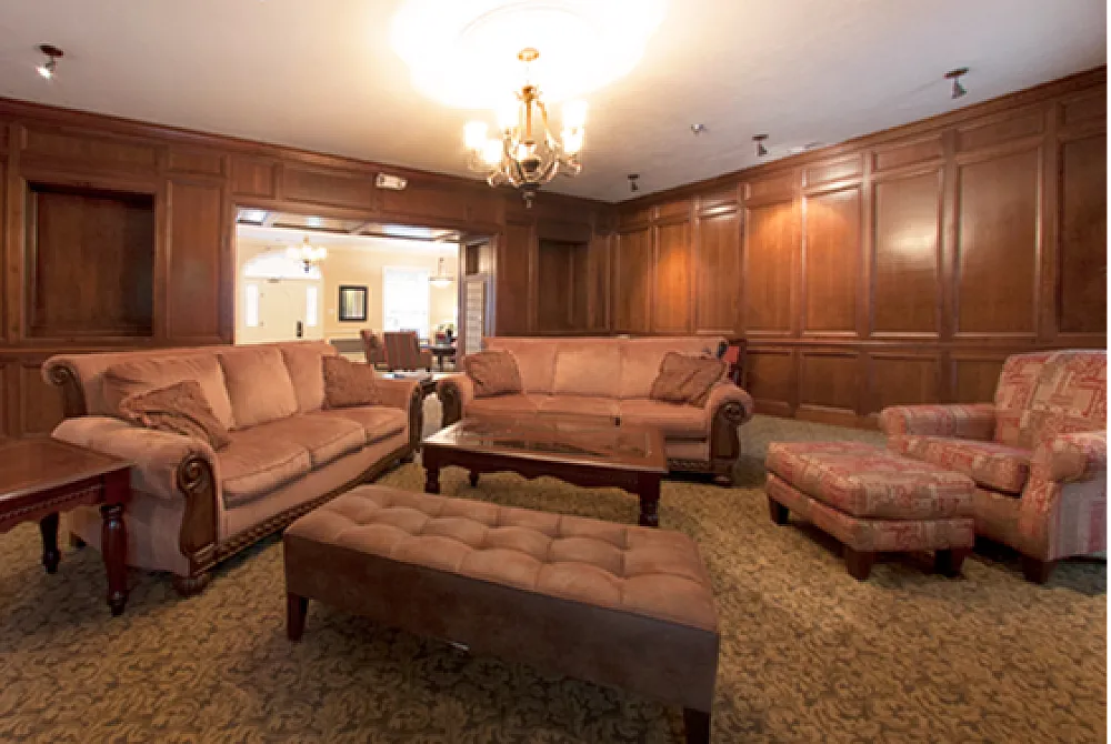 Elegant living room with rich wood paneling, plush sofas, and ambient chandelier lighting creating a warm, inviting atmosphere.