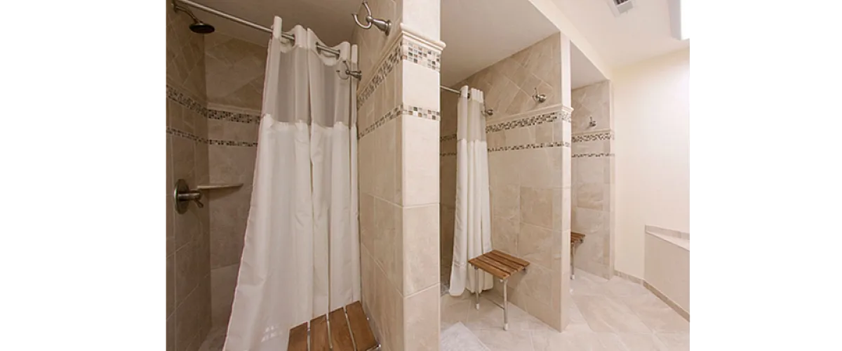 Elegant modern bathroom with three spacious shower stalls featuring stylish tilework and convenient seating.