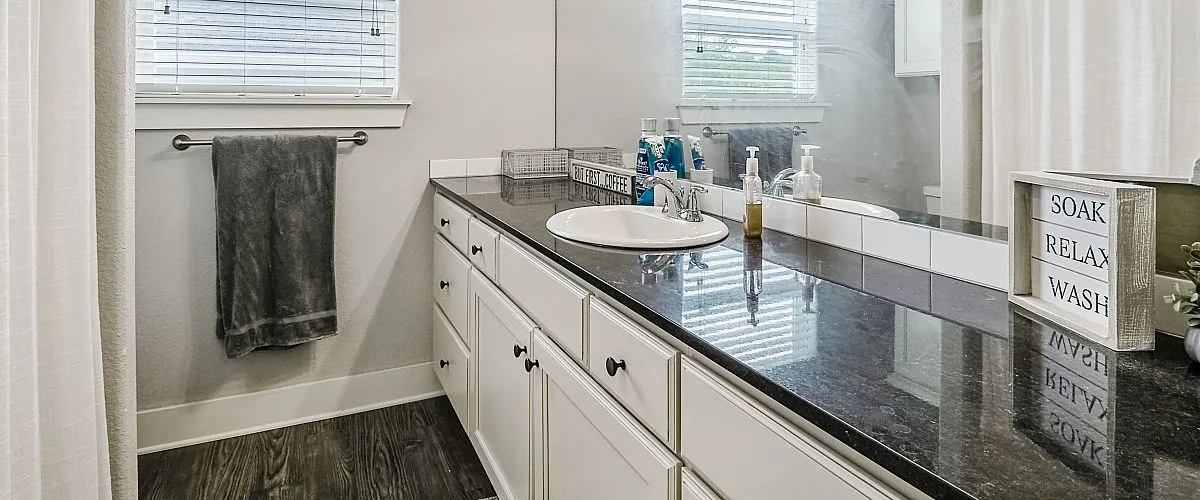 Modern bathroom with elegant black granite countertop, stylish lighting, and relaxing decor.