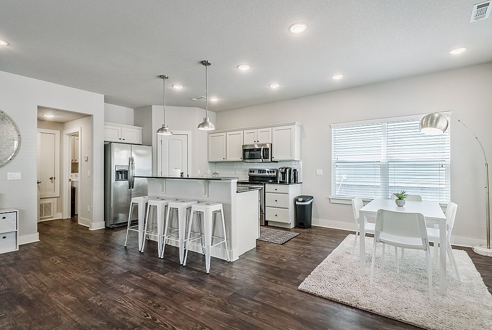 Modern open-plan kitchen and dining area with sleek appliances, stylish bar seating, and ample natural light.