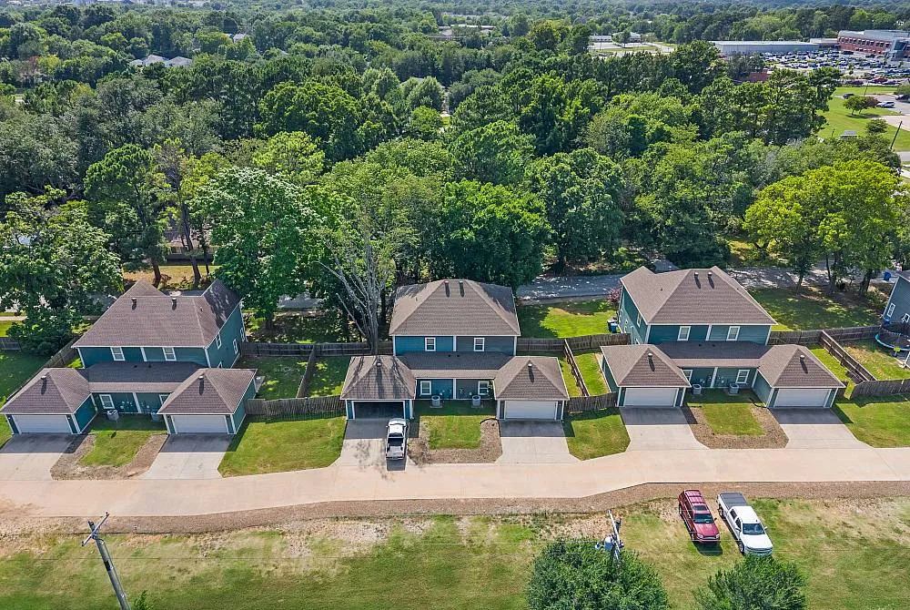 Aerial view of charming houses with green roofs and lush trees in a picturesque suburban neighborhood.