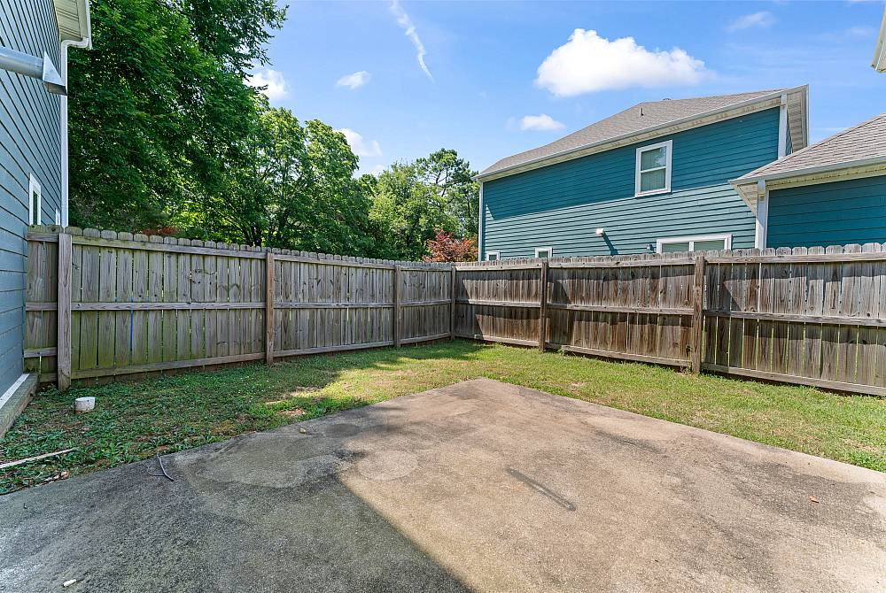 Charming backyard patio with privacy fence, ideal for outdoor relaxation, surrounded by lush greenery.