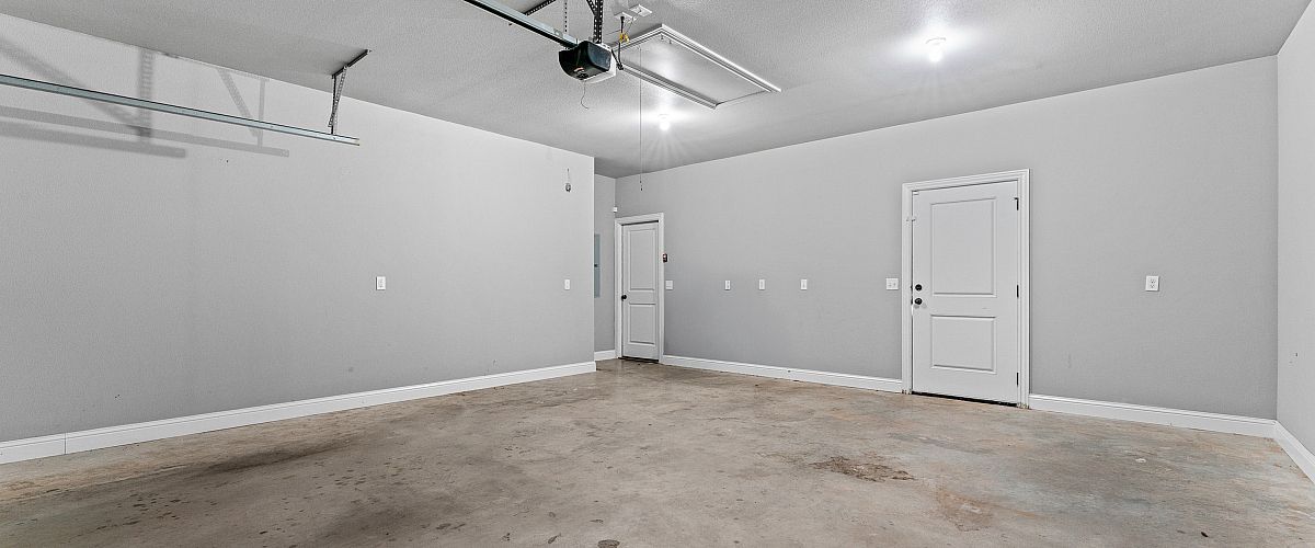 Spacious, clean garage with sleek concrete flooring and modern ceiling lighting, ready for customization.