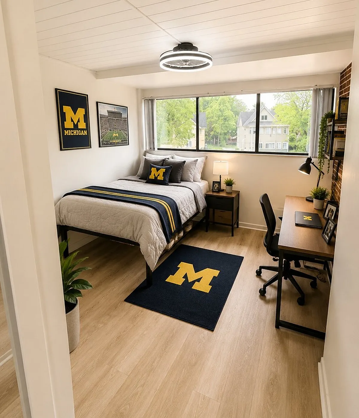 Bright and inviting bedroom featuring modern decor with university-themed accents, hardwood flooring, and a large window offering lush green views.