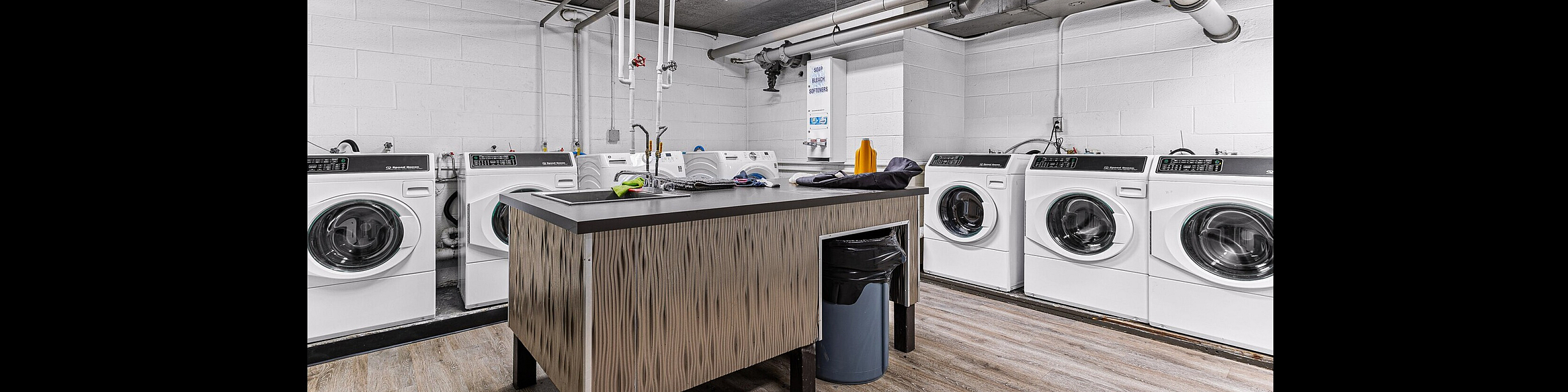 Modern laundry room with state-of-the-art washing machines and stylish countertops, featuring ample natural light and sleek design.