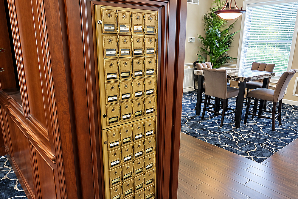 Elegant apartment lobby featuring classic wooden mailboxes and a chic dining area with plush seating, ideal for social gatherings.