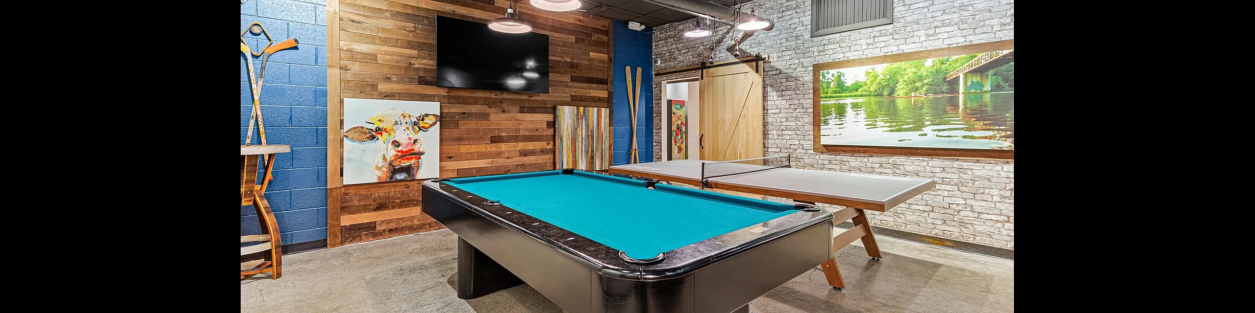 Chic recreational room with a stylish pool table, vibrant artwork, and a cozy lodge ambiance.