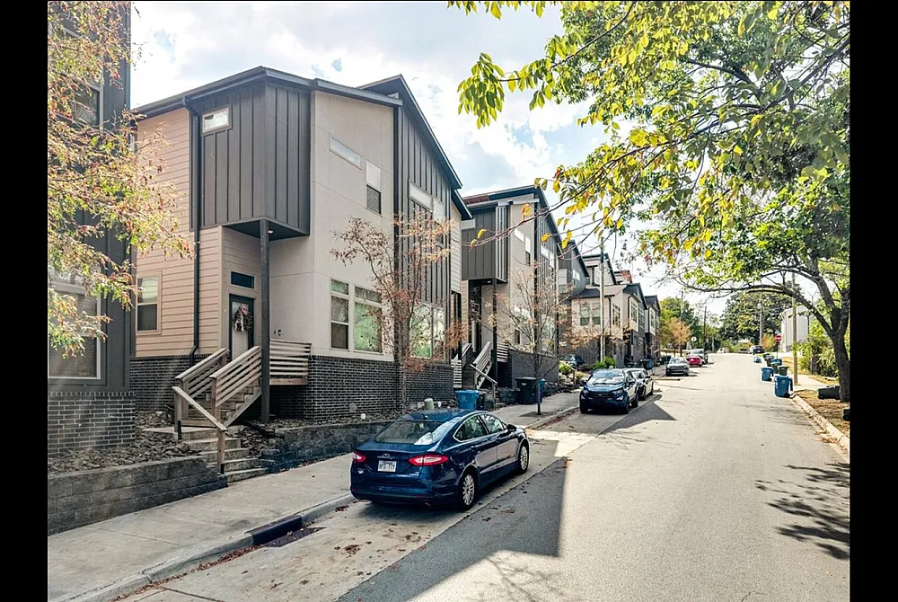 Charming urban street with modern townhouses and lush green foliage, perfect for contemporary city living.