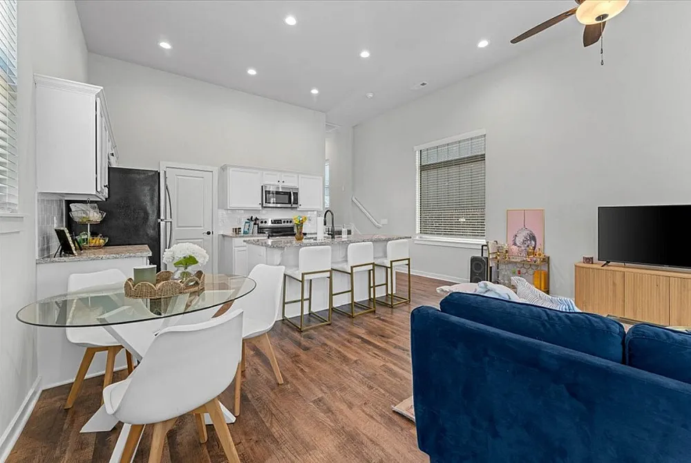 Chic open-plan living area with a modern kitchen featuring a breakfast bar, elegant dining set, and cozy lounge space with stylish decor.