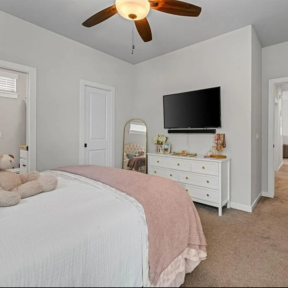 Inviting bedroom with plush carpeting, stylish white dresser, and cozy ambiance perfect for relaxation.