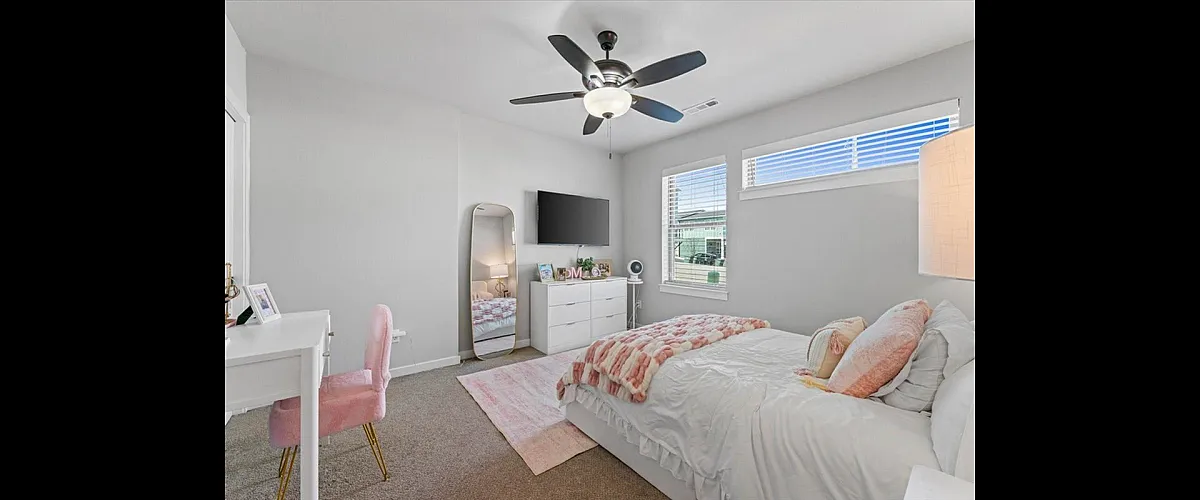 Inviting bedroom with plush pink decor, elegant mirror, and ample natural light from large windows.