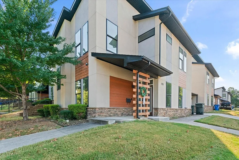 Modern townhouse exterior with stylish architectural design, large windows, and landscaped front yard.