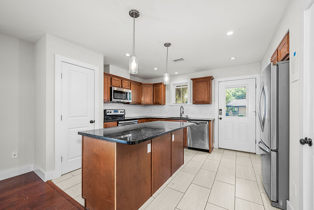Modern kitchen with sleek granite countertops, stainless steel appliances, and warm wood cabinetry, offering a bright and inviting space.