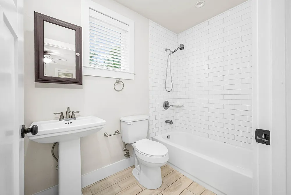 Bright, modern bathroom featuring elegant white subway tiles, a stylish vanity mirror, and a sleek white pedestal sink.