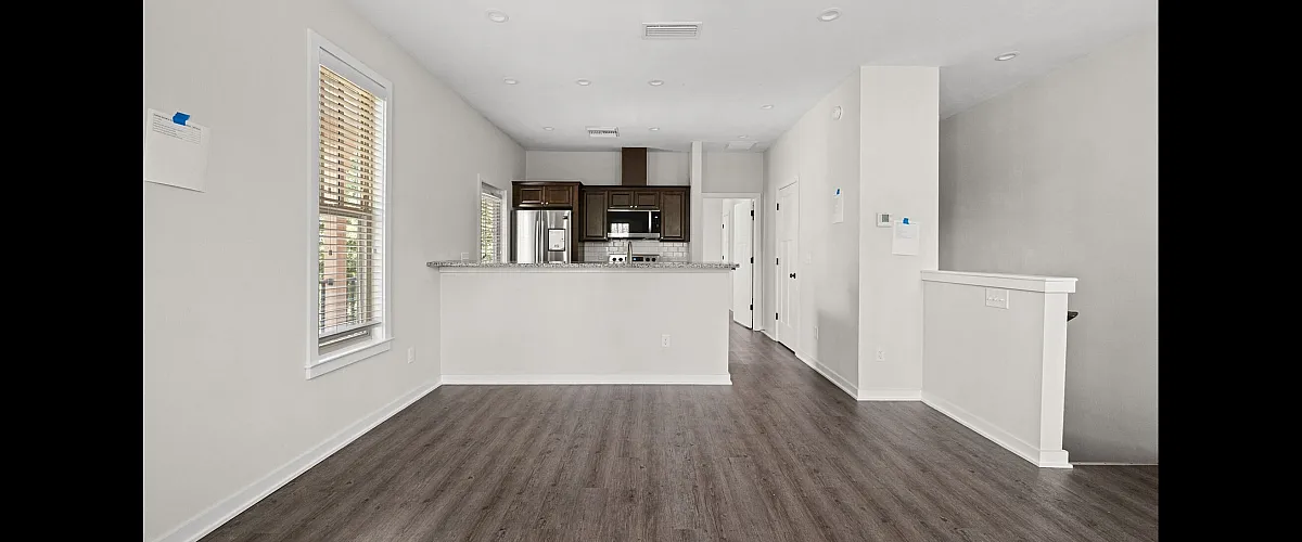 Modern open-concept living area with a sleek kitchen featuring stainless steel appliances, elegant dark cabinetry, and stylish wood flooring.