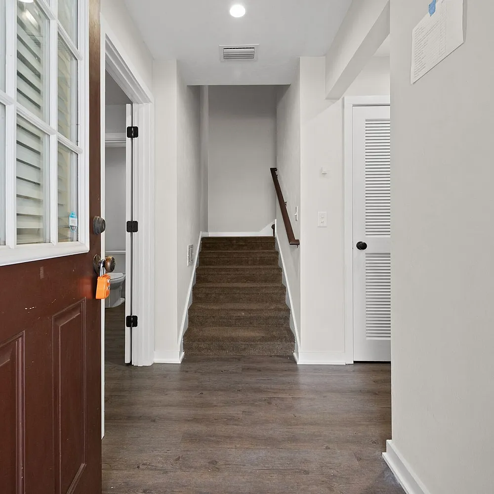 Inviting entryway with wooden floors leading to a cozy staircase in a modern apartment.