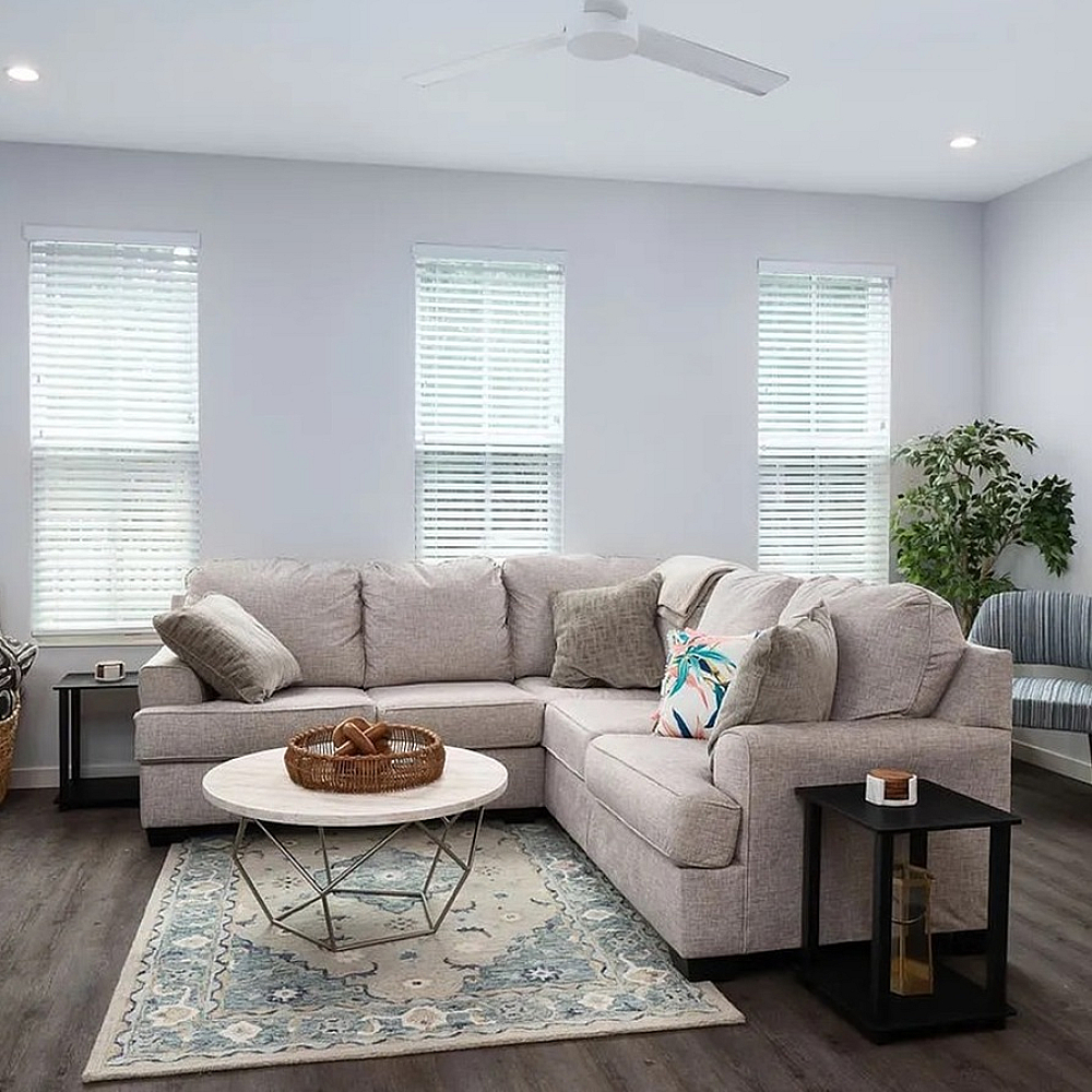 Modern open-concept living area with sleek hardwood floors, bright natural light, and a polished kitchen island featuring a double sink.