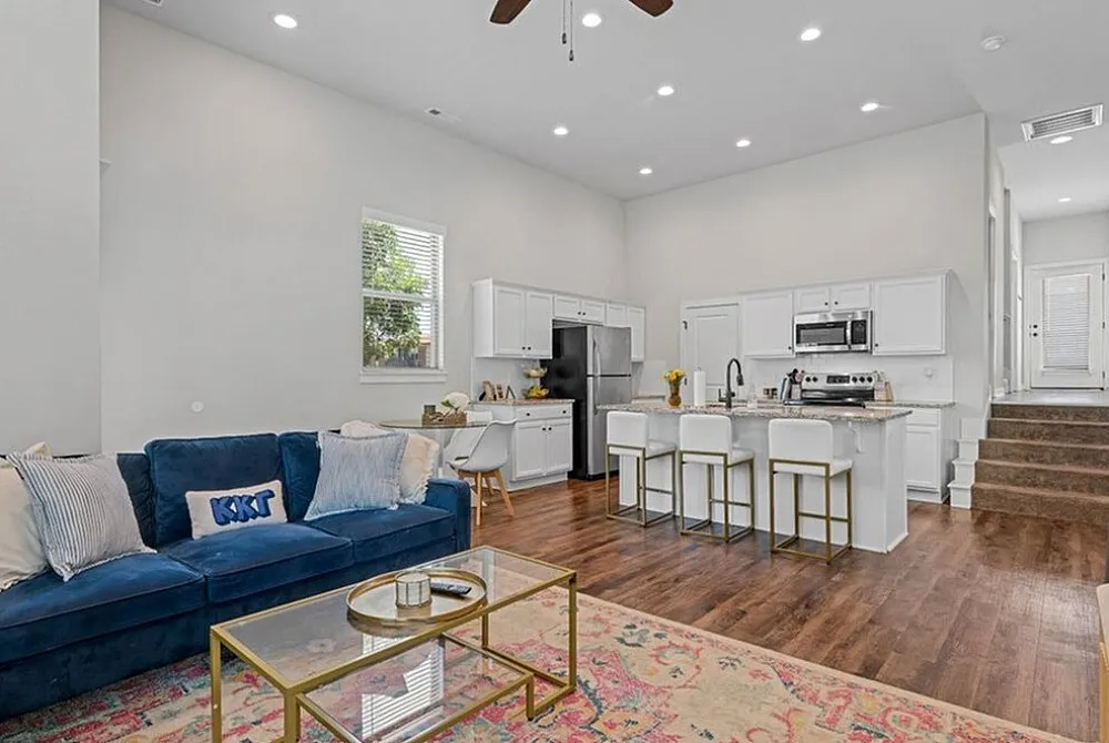 Chic open-plan living area with a modern kitchen featuring a breakfast bar, elegant dining set, and cozy lounge space with stylish decor.