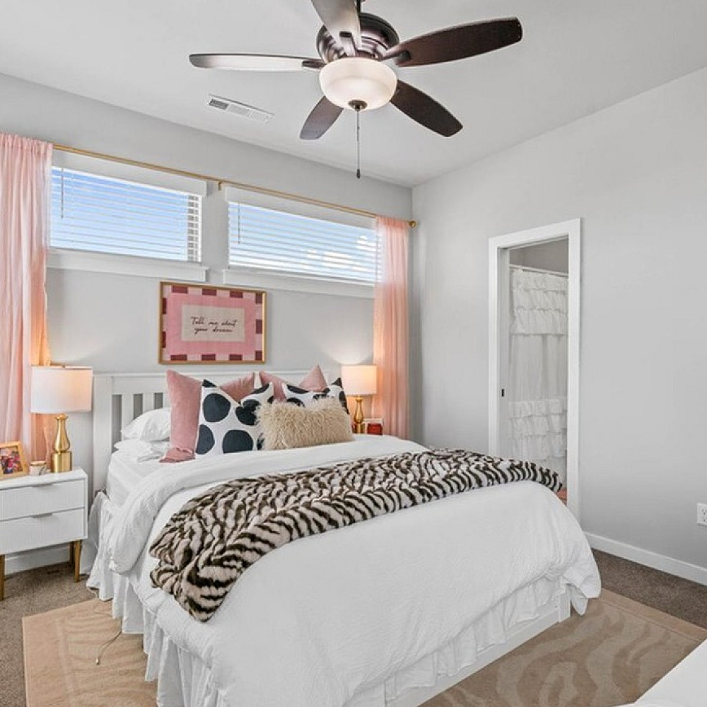 Inviting bedroom with plush carpeting, stylish white dresser, and cozy ambiance perfect for relaxation.