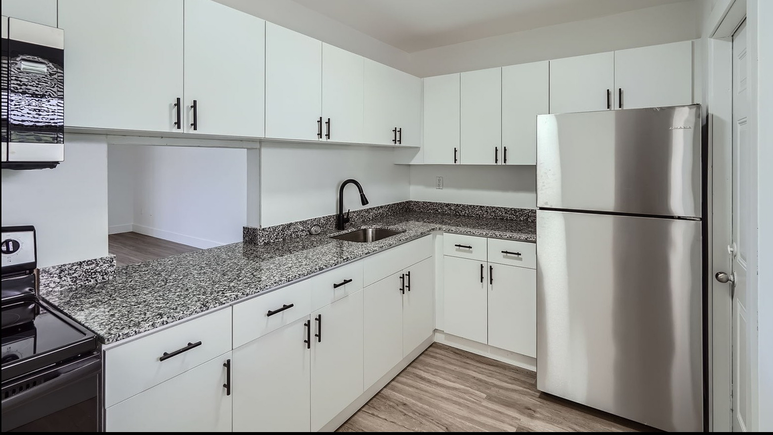 Modern kitchen with sleek stainless steel appliances, granite countertops, and stylish white cabinetry for your culinary adventures.