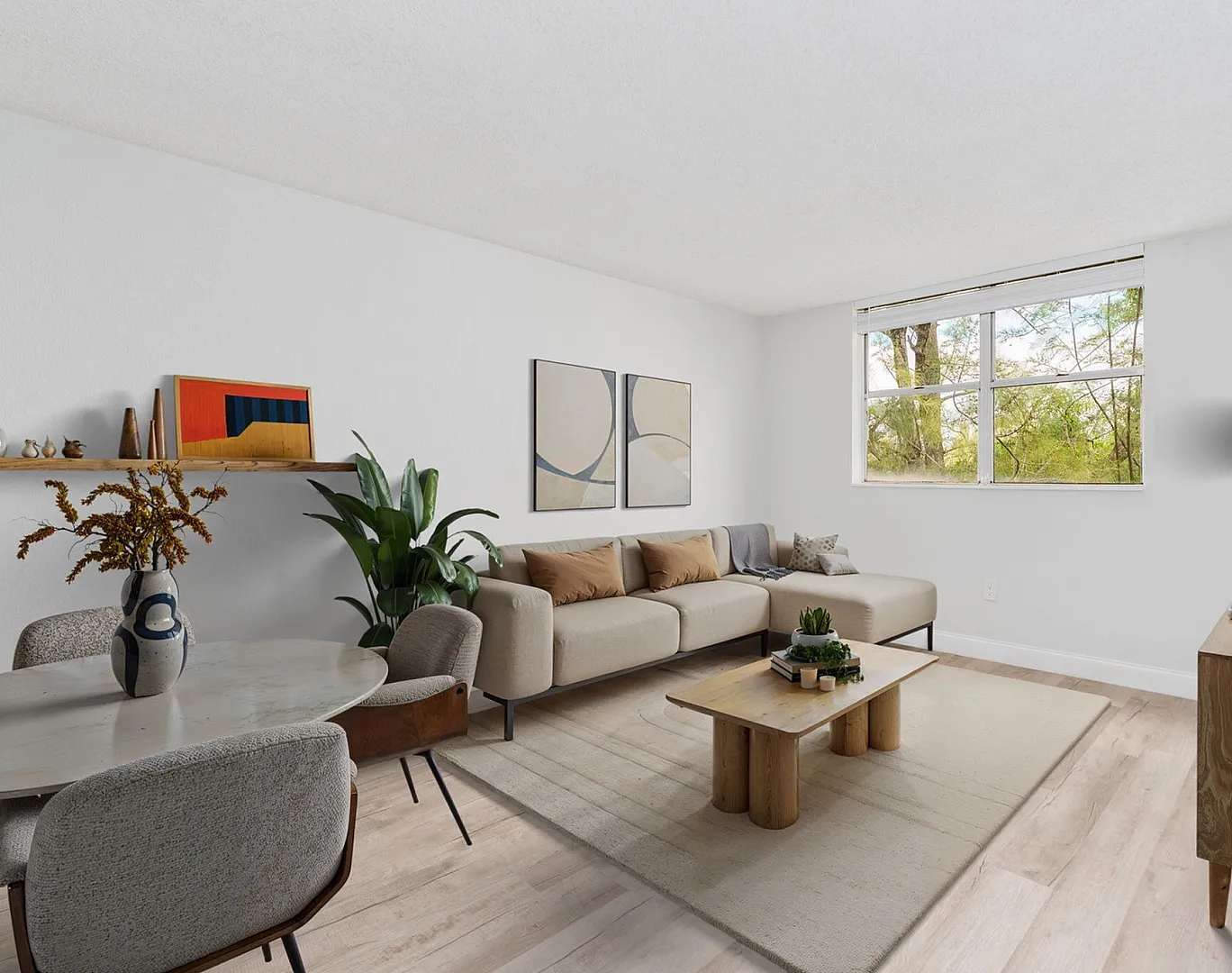 Inviting living room with modern furnishings, cozy sectional sofa, chic dining area, and large window with lush green views.