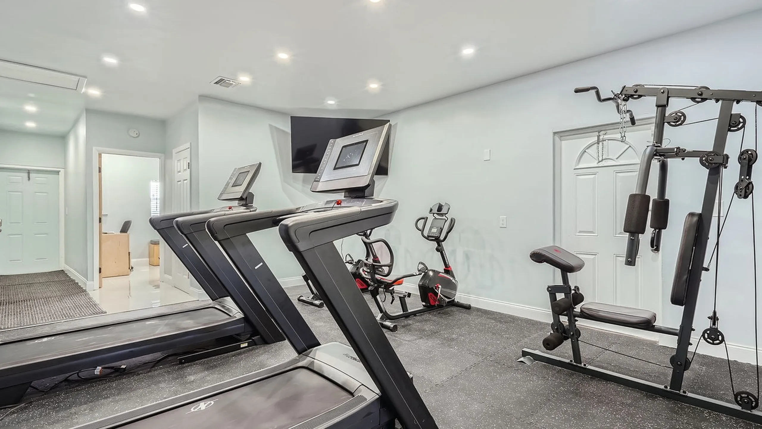 Modern home gym featuring state-of-the-art treadmills, exercise bike, and strength training equipment in a bright, inviting space.