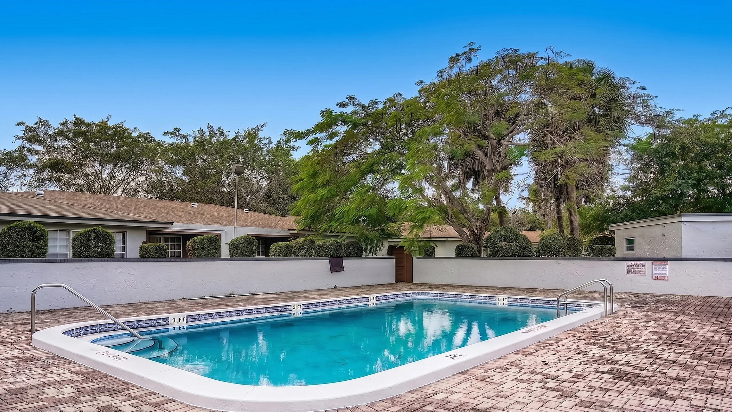 Inviting residential swimming pool surrounded by lush greenery and modern patio, perfect for relaxation and leisure.