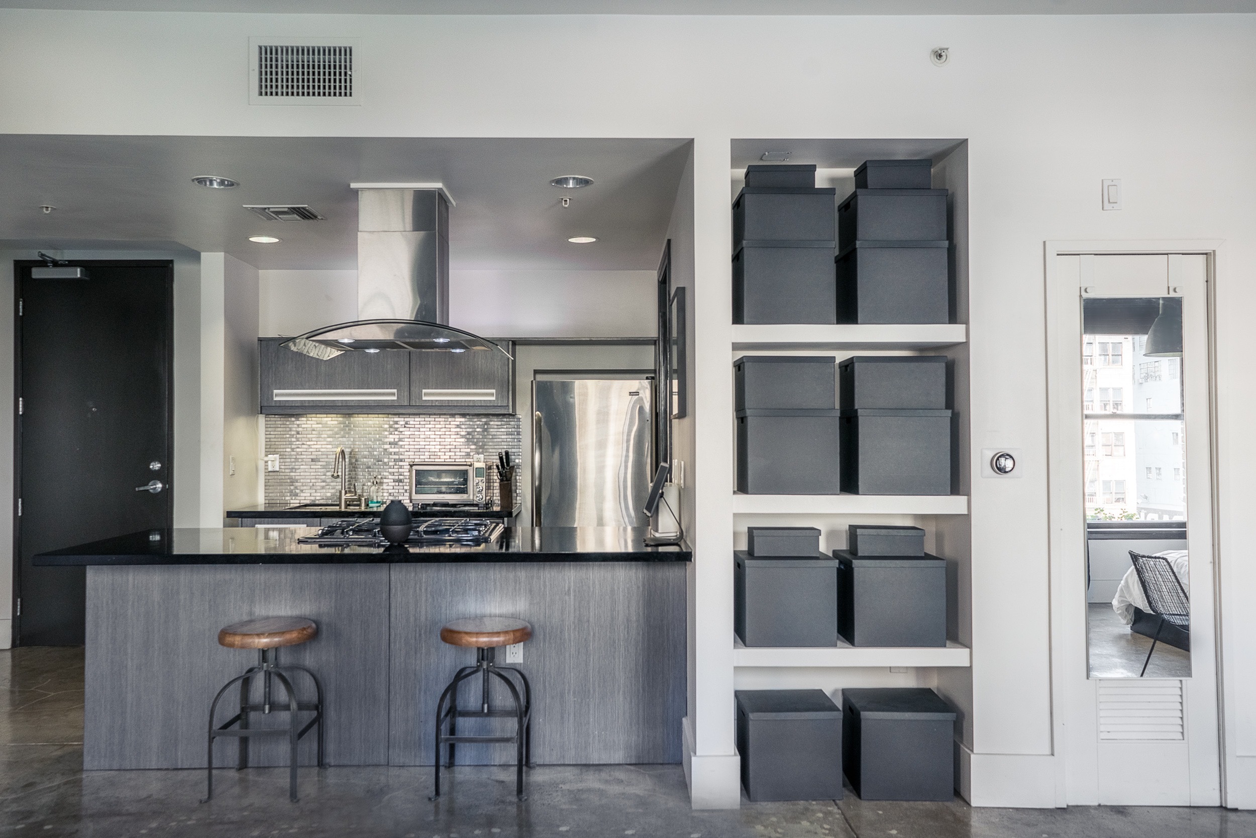 Modern kitchen with sleek countertops, stylish backsplash, and elegant storage solutions. Features stainless steel appliances and a cozy bar area with two stools.