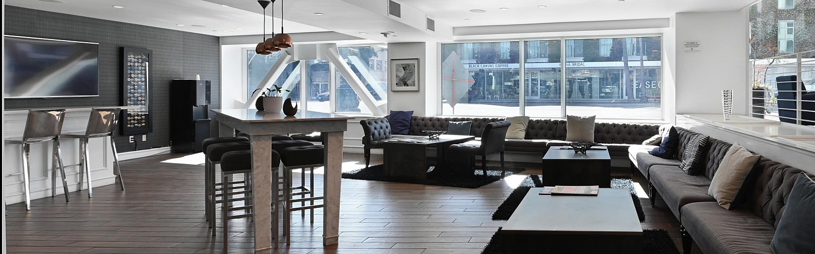 Modern open-concept lounge with sleek furniture, wooden flooring, and abundant natural light.