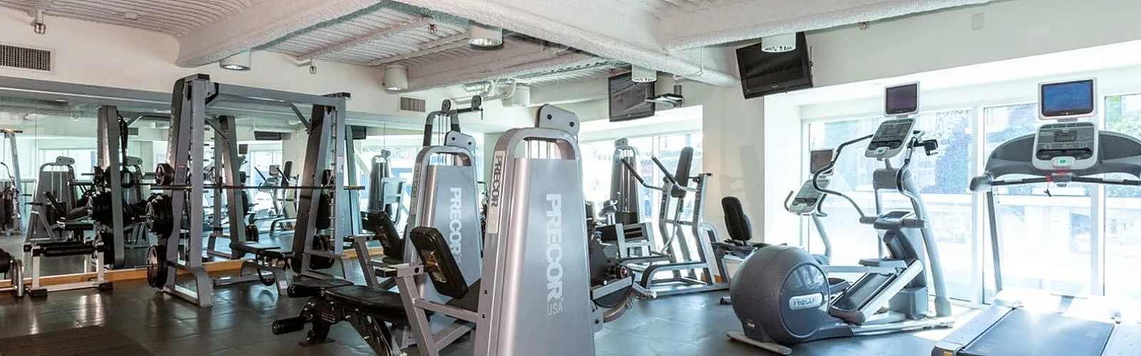 Bright and modern gym with state-of-the-art exercise machines including treadmills, weight machines, and ellipticals.