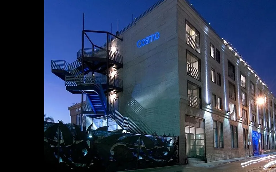 Modern apartment building at dusk with vibrant blue exterior lights and architectural staircase.