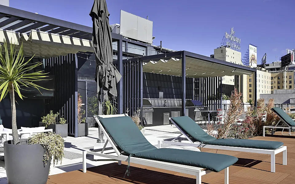 Chic rooftop terrace with sun loungers, modern pergola, and city view.