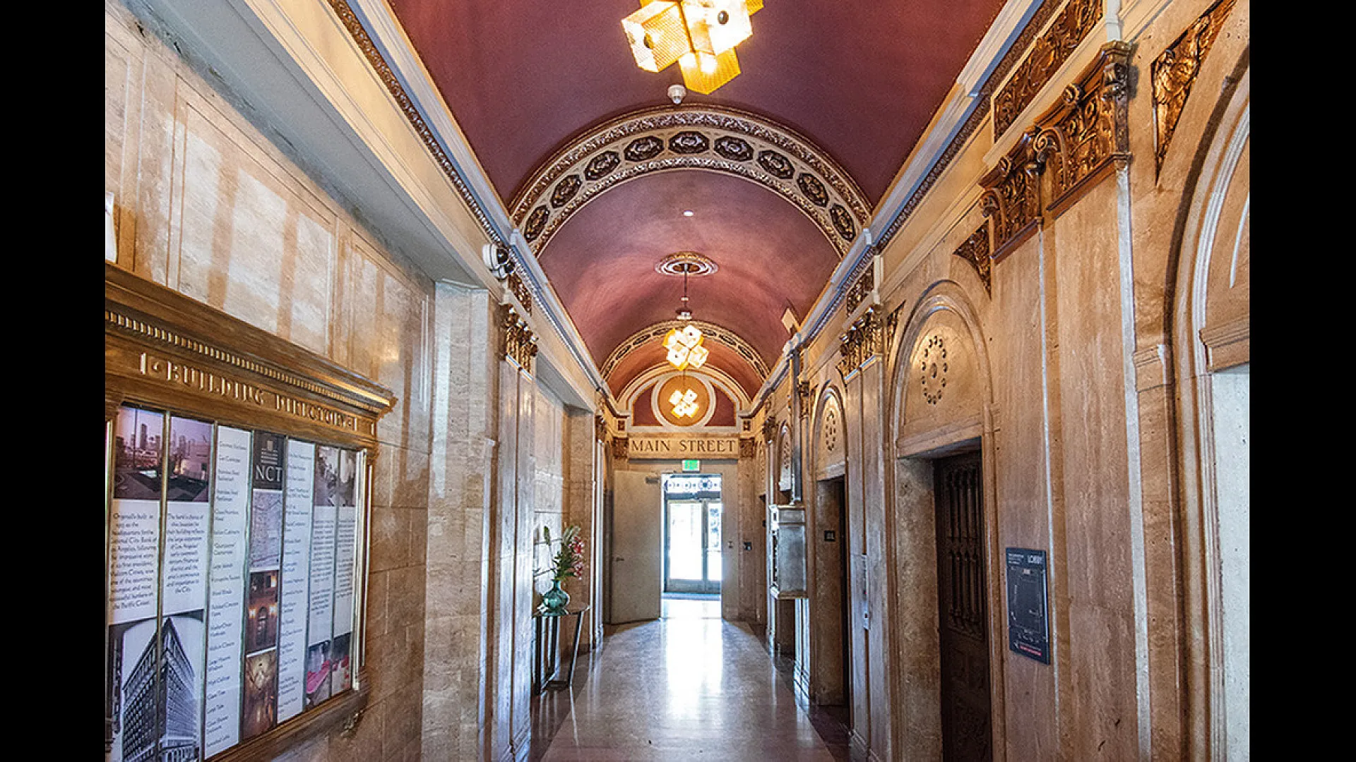 Elegant hallway with ornate ceiling and vintage decor leading to Main Street entrance, featuring historical charm and architectural beauty.