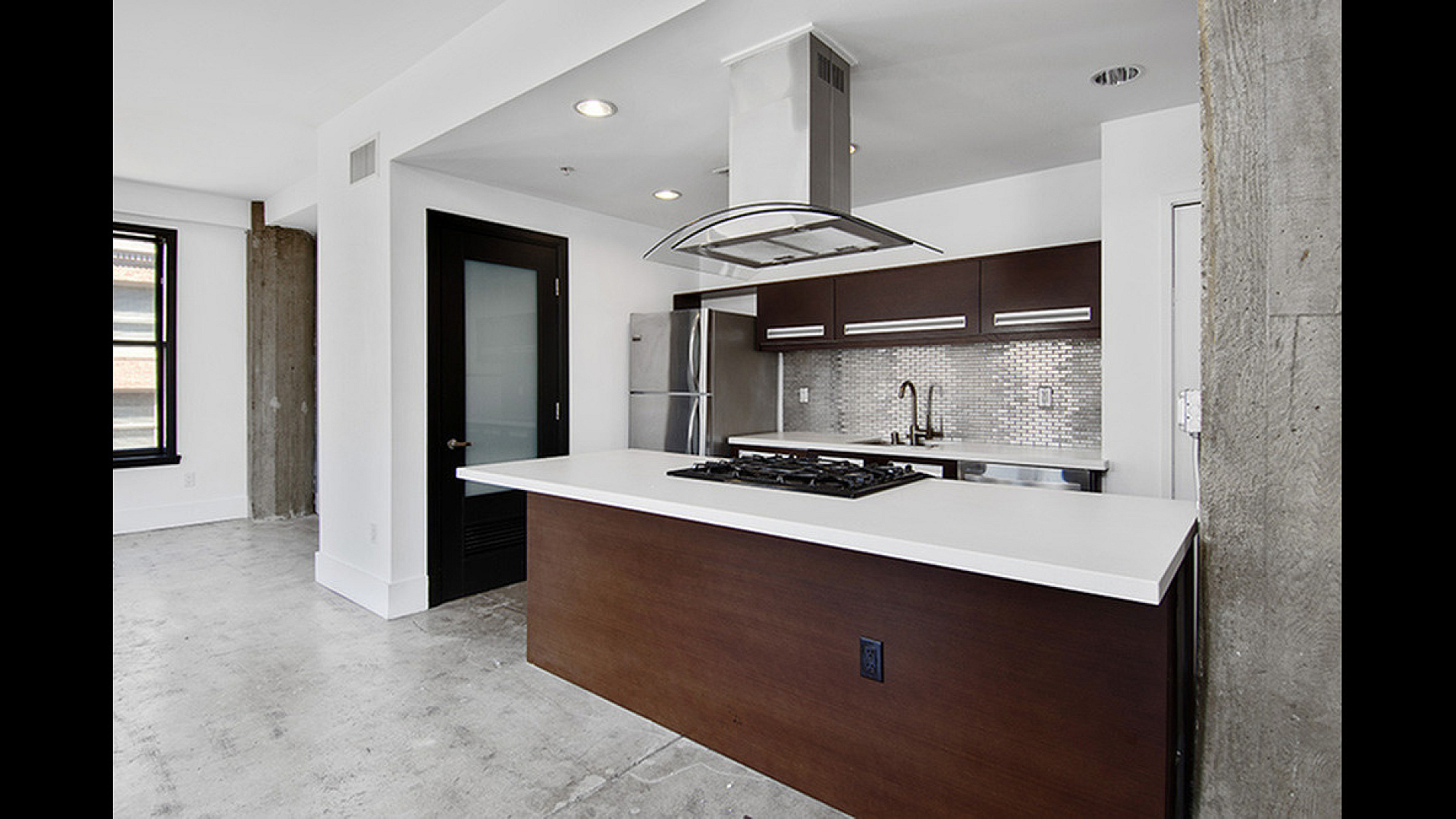 Modern kitchen space featuring sleek stainless steel appliances, chic dark wood cabinets, and a contemporary open layout.