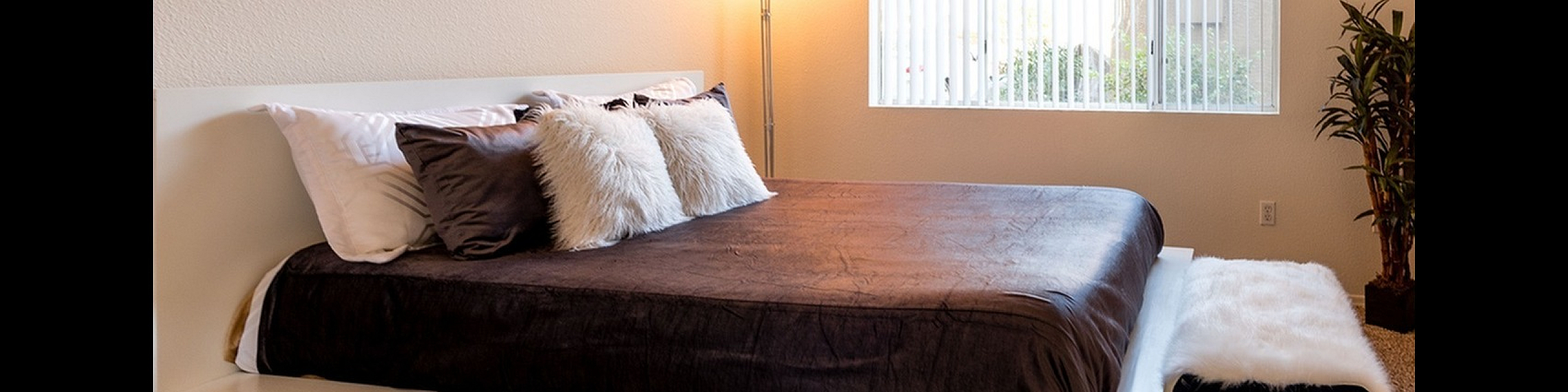 Inviting bedroom with modern platform bed, elegant decor, and large window for natural light.