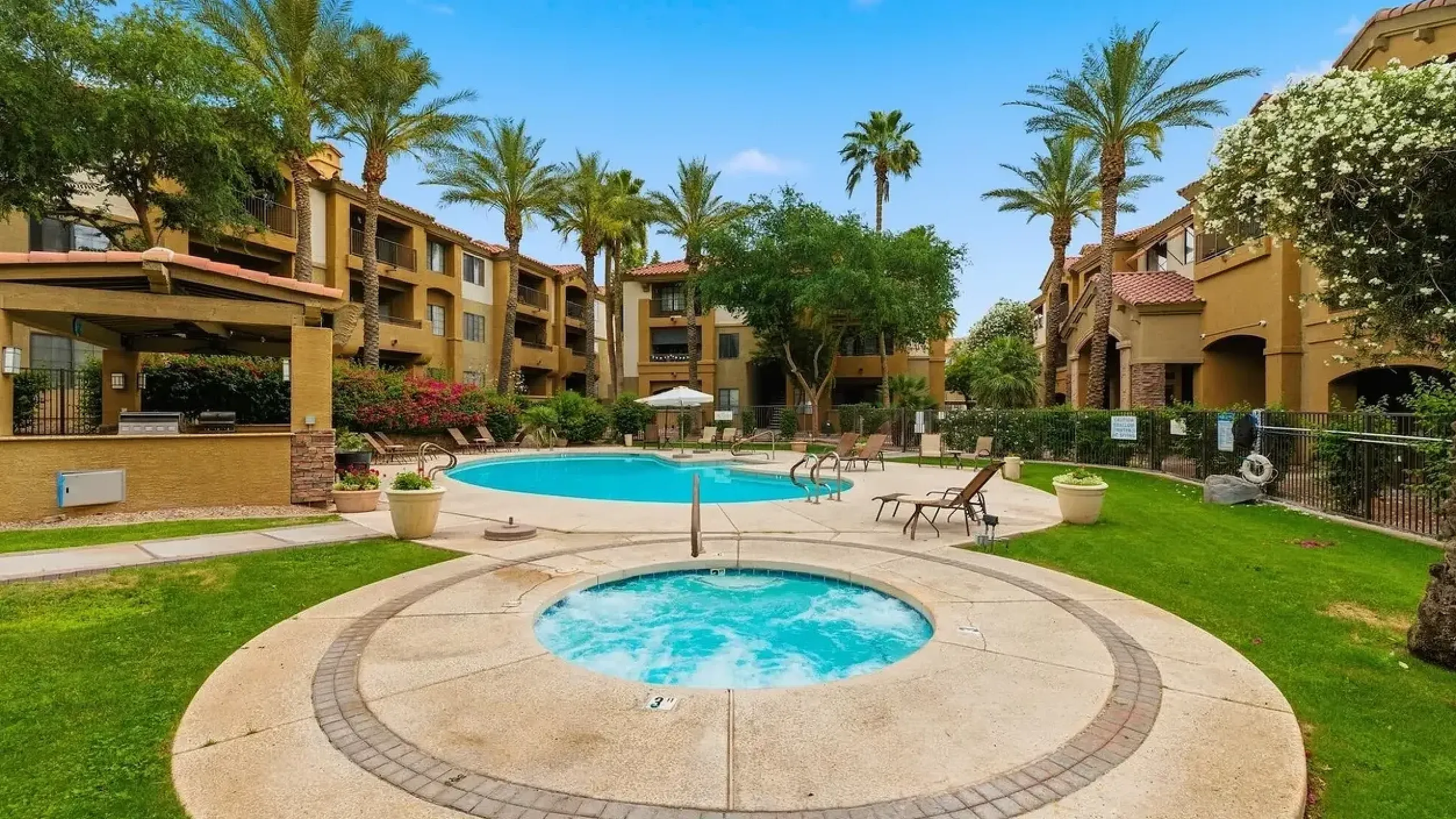 Inviting entrance to a luxury apartment complex, surrounded by vibrant landscaping and towering palm trees, featuring the Belaflora sign.