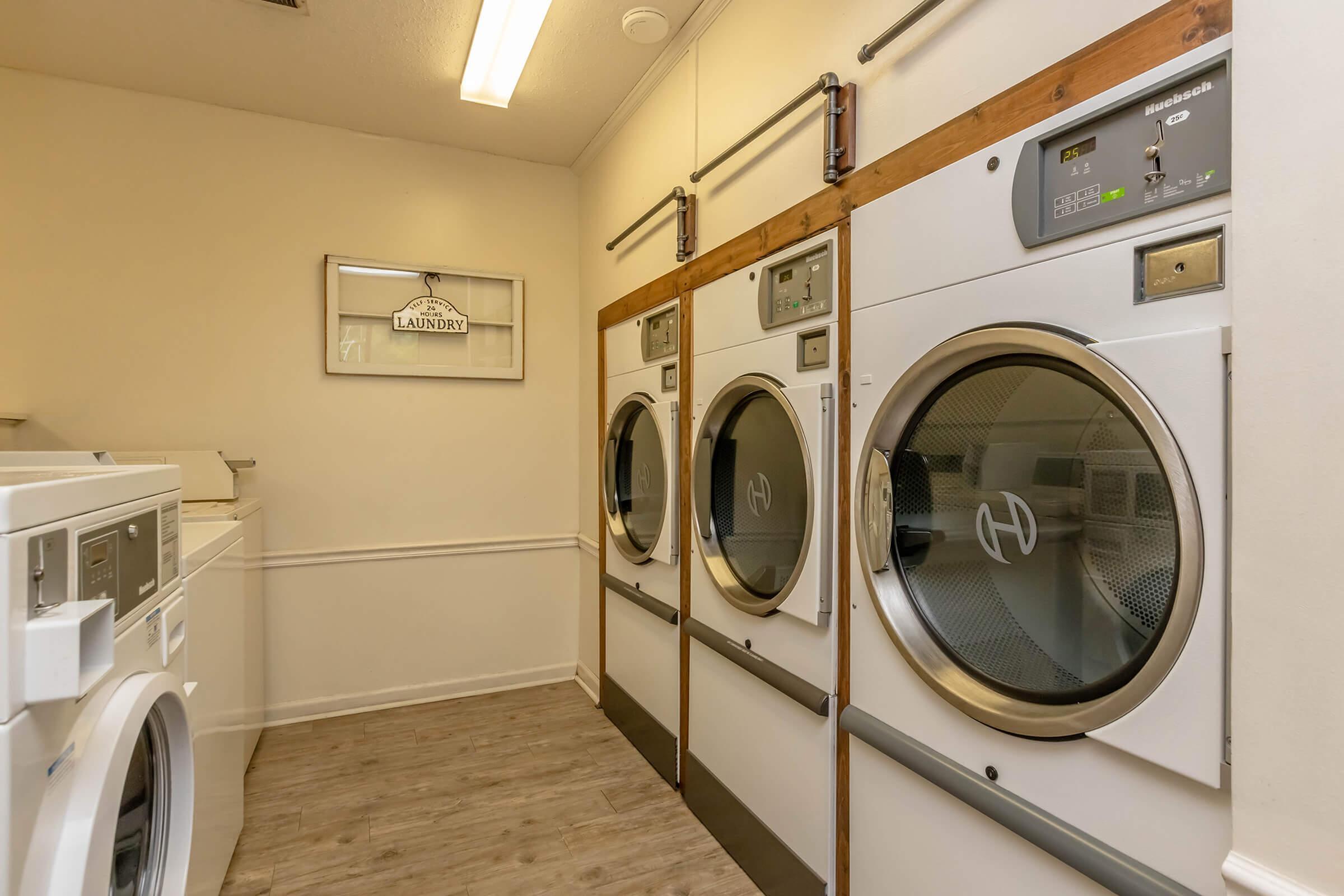 Bright and efficient laundry room featuring modern stacked washers and dryers, complemented by stylish wood accents on the machines.