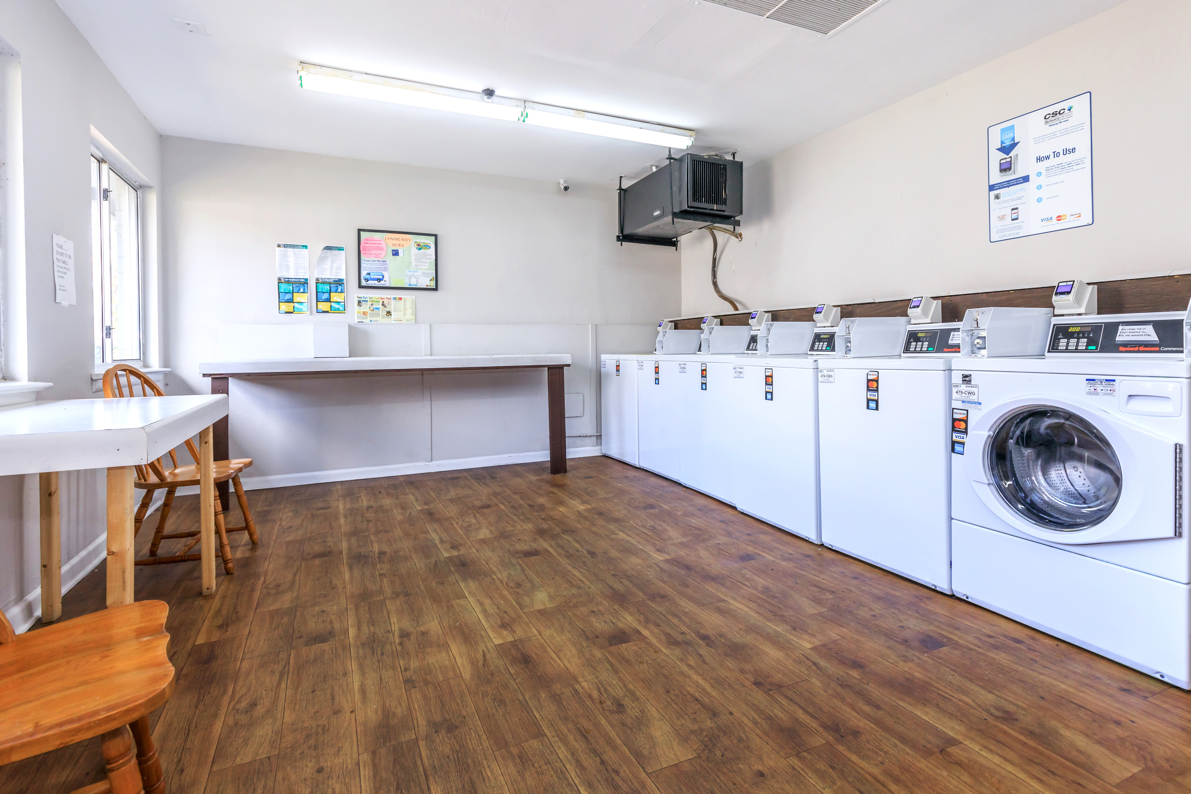 Bright and spacious laundry room with modern washing machines, stylish wood flooring, and ample seating.