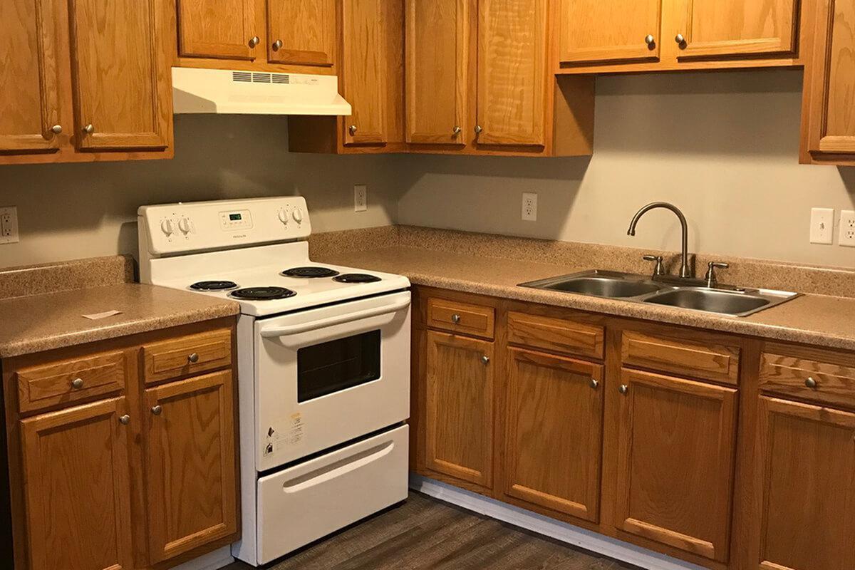 Charming kitchen with warm wooden cabinetry, modern appliances, and sleek countertops ideal for cozy cooking experiences.
