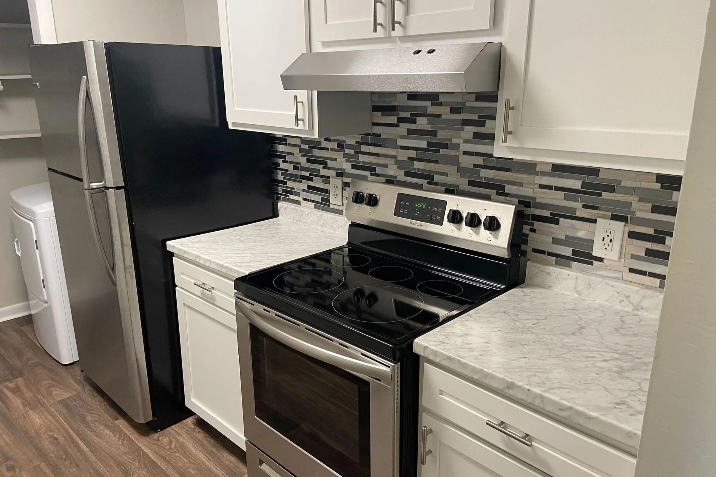 Modern kitchen with sleek stainless steel appliances, elegant white cabinetry, and a chic tiled backsplash for a stylish finish.